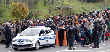 Slovenian policemen escort a group of migrants from a train towards a camp in Sentilj, Slovenia, Friday, Oct. 23, 2015. Thousands of people are trying to reach central and northern Europe via the Balkans but often have to wait for days in mud and rain at the Serbian, Croatian and Slovenian borders. (AP Photo/Petr David Josek)